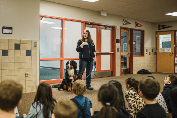 Cathy and her dog Sully present in front of a group of elementary students
